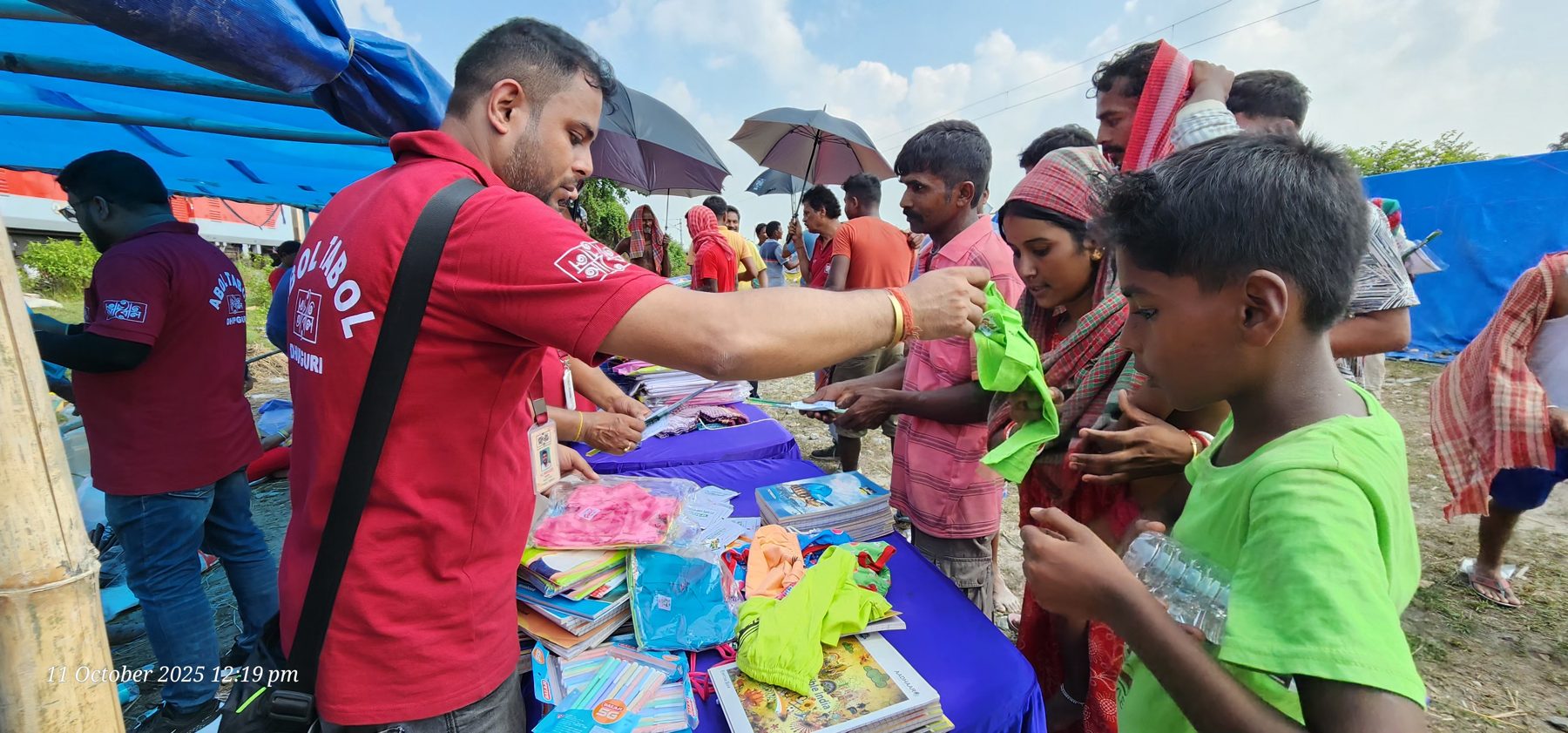 A volunteer handing packets to children at a relief camp