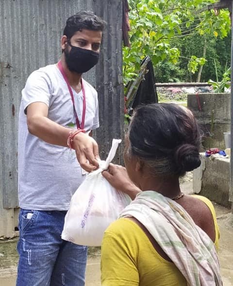 Masked volunteer handing a relief packet to a woman during COVID-19