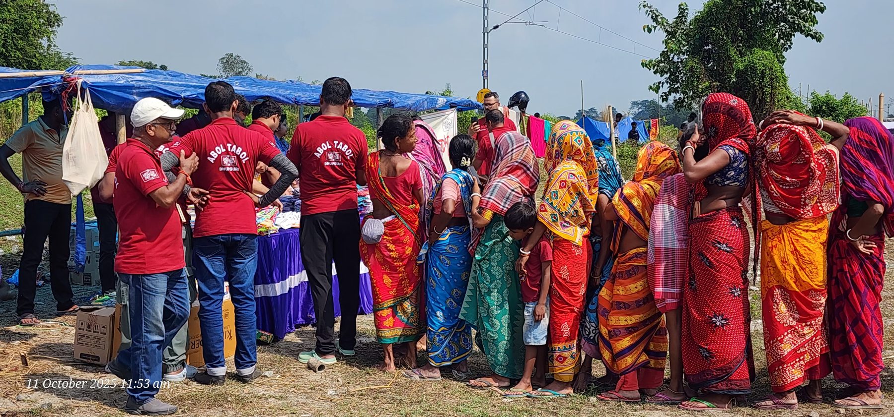 Families waiting in line to receive relief materials beside temporary shelters